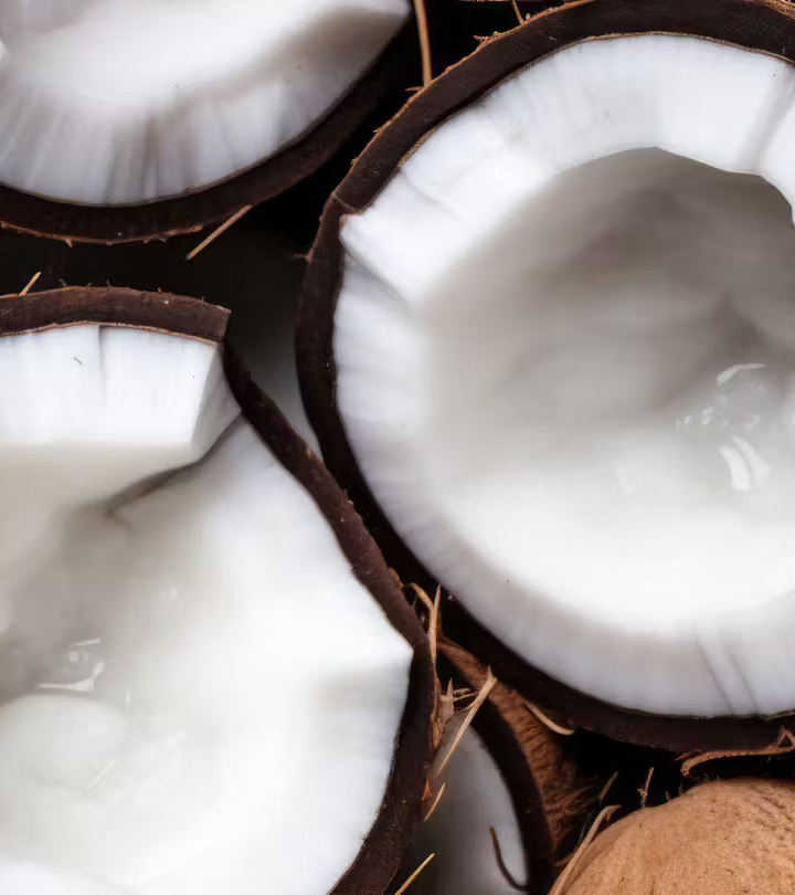 Close-up of several halved coconuts showing white flesh and dark brown shells